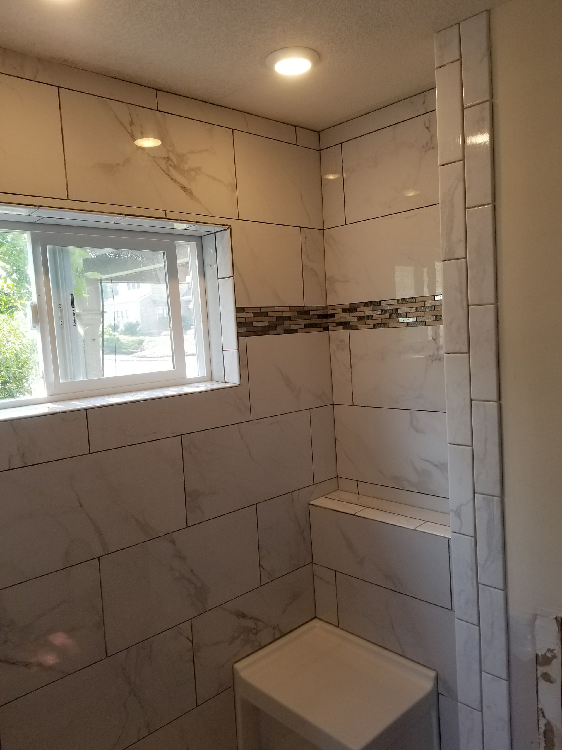 Douglas Biltzen's DB Builders modern tiled shower in Eureka, CA with integrated window and custom bench